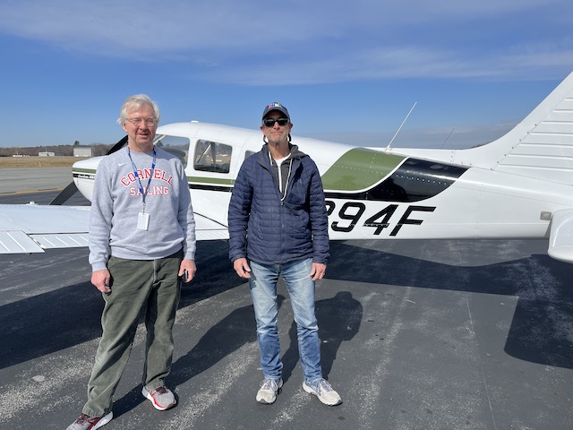 A couple of men standing in front of a small airplane

Description automatically generated with low confidence
