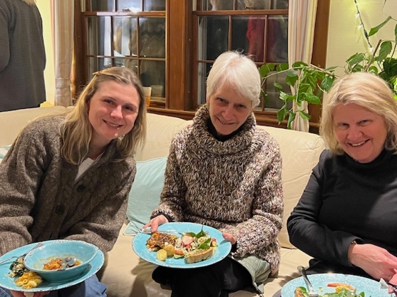 A group of women sitting on a couch with plates of food

Description automatically generated