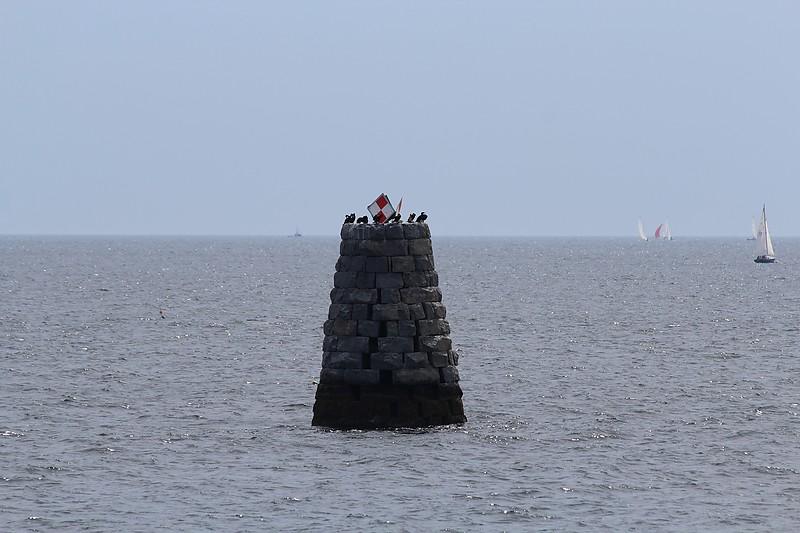 A stone tower in the middle of the oceanDescription automatically generated