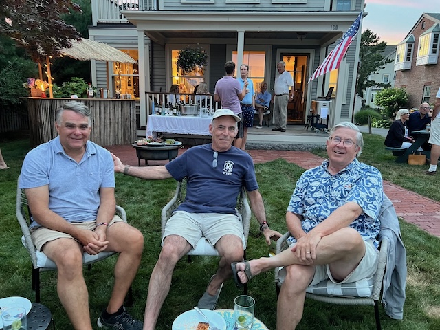 A group of men sitting in chairs outside a houseDescription automatically generated